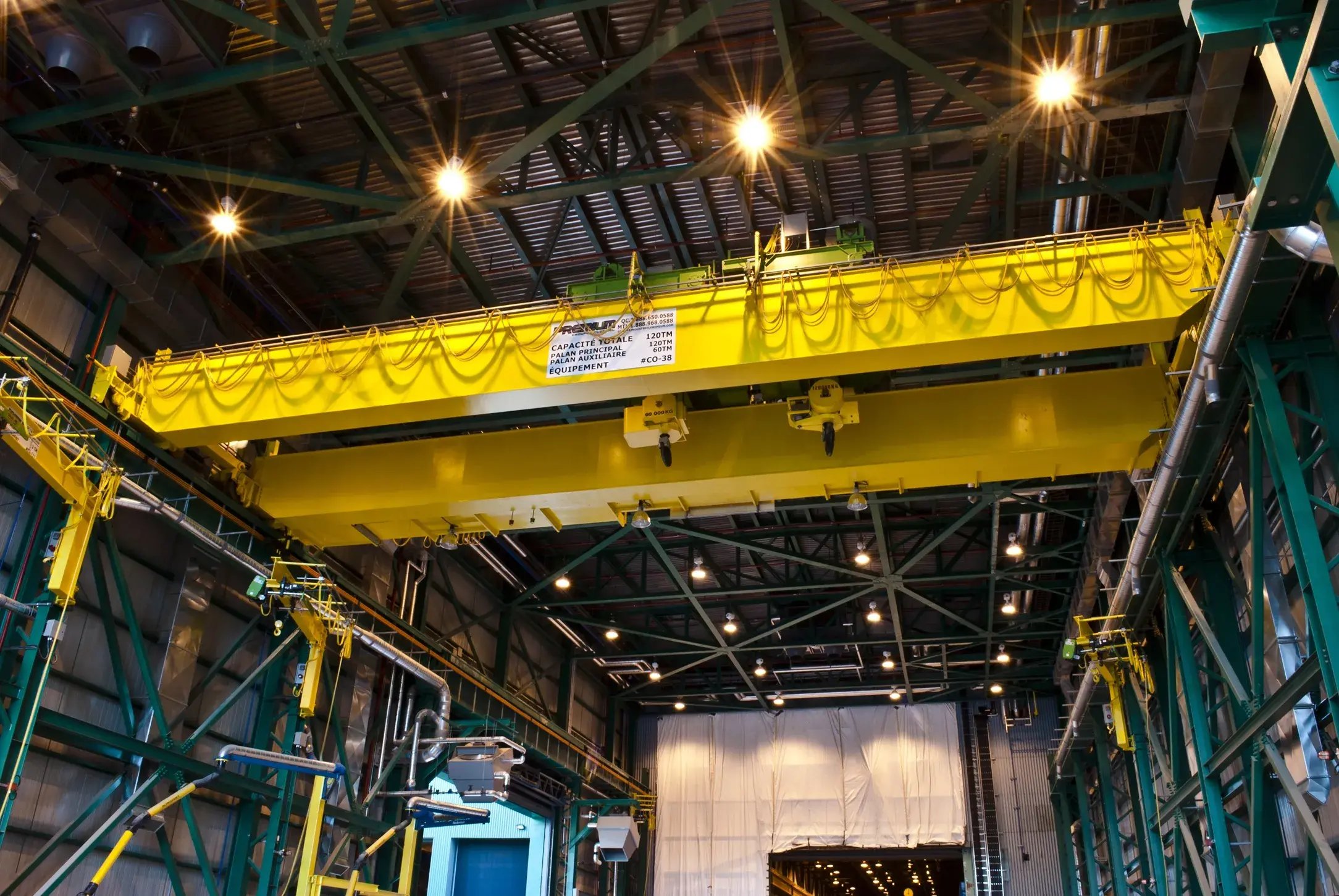 pont roulant double-poutre équipé d'un palan treuil ouvert ainsi que plusieurs potences dans une usine
