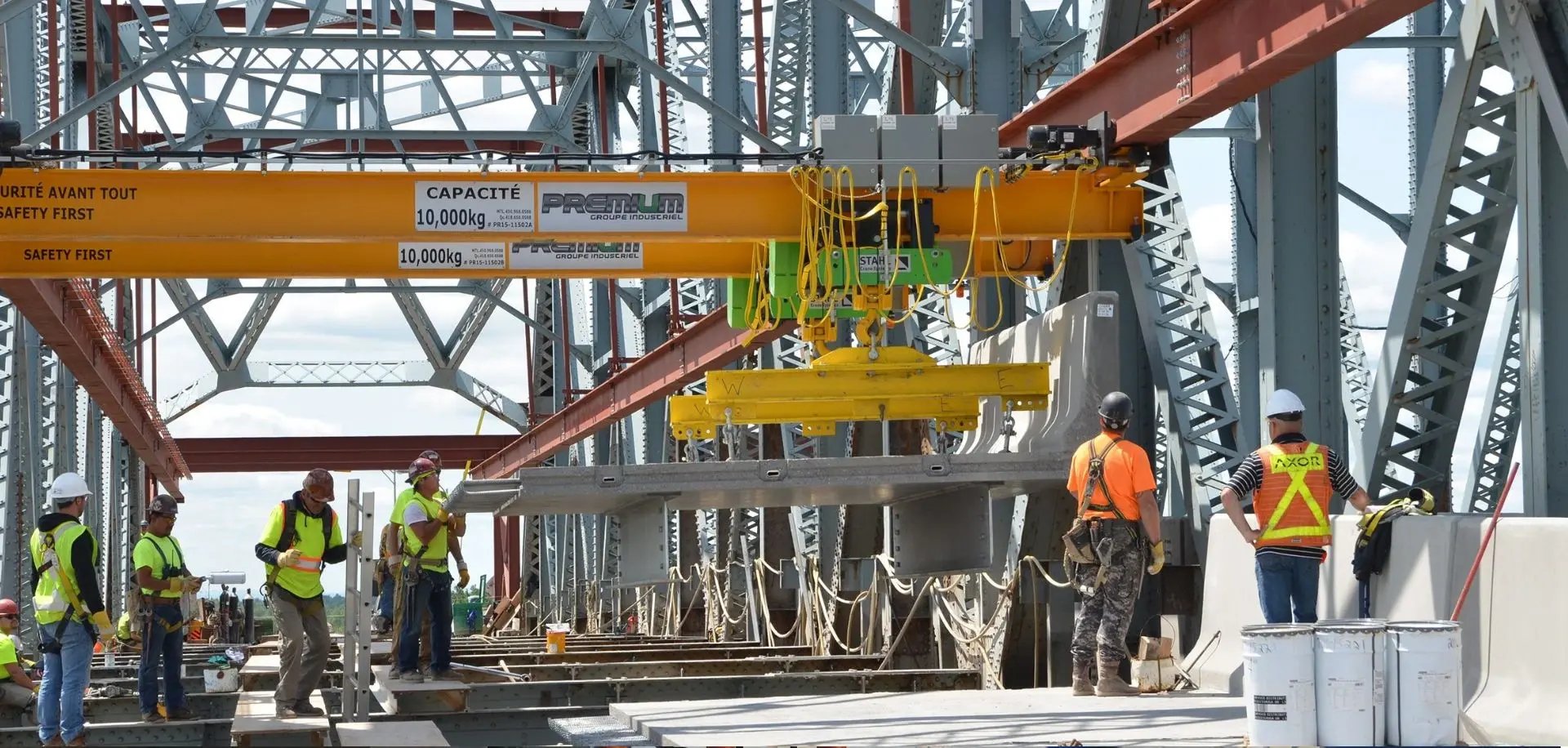 travailleurs soulevant une charge avec un pont roulant suspendu