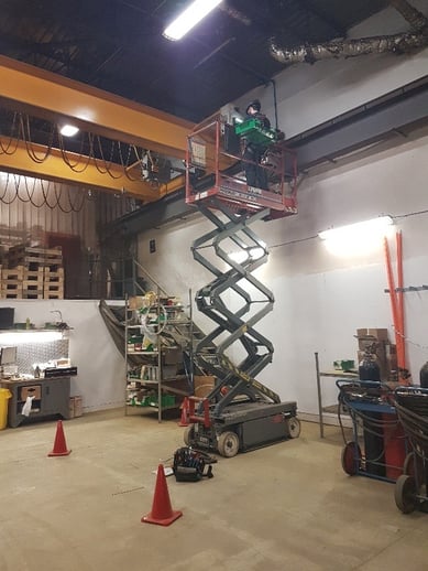 ouvrier dans une nacelle élévatrice effectuant l'entretien d'un pont roulant