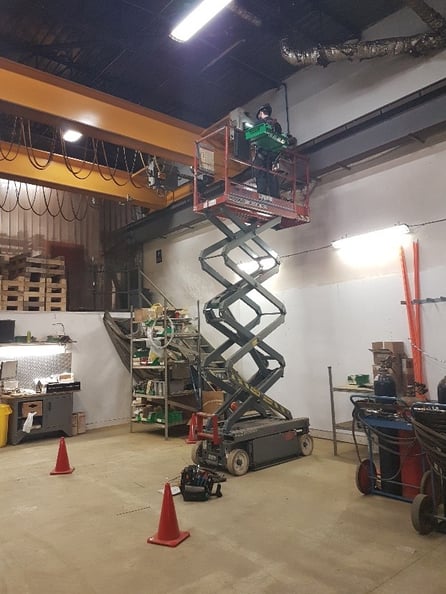 ouvrier dans une nacelle élévatrice effectuant l'entretien d'un pont roulant