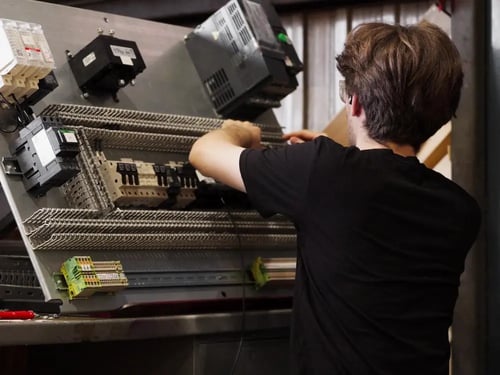 personne-assemblage-panneau-electrique-production