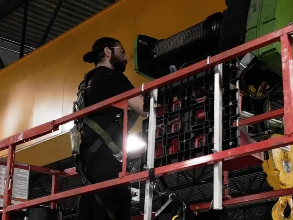 une personne équipé d'un harnet de sécurité effectuant une inspection de pont roulant